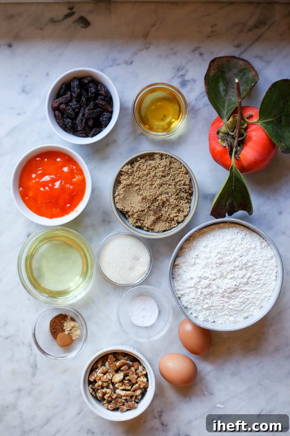 Individual bowls neatly arranged on a marble counter, showcasing all the fresh ingredients needed to bake homemade persimmon bread, from spices to fruit.