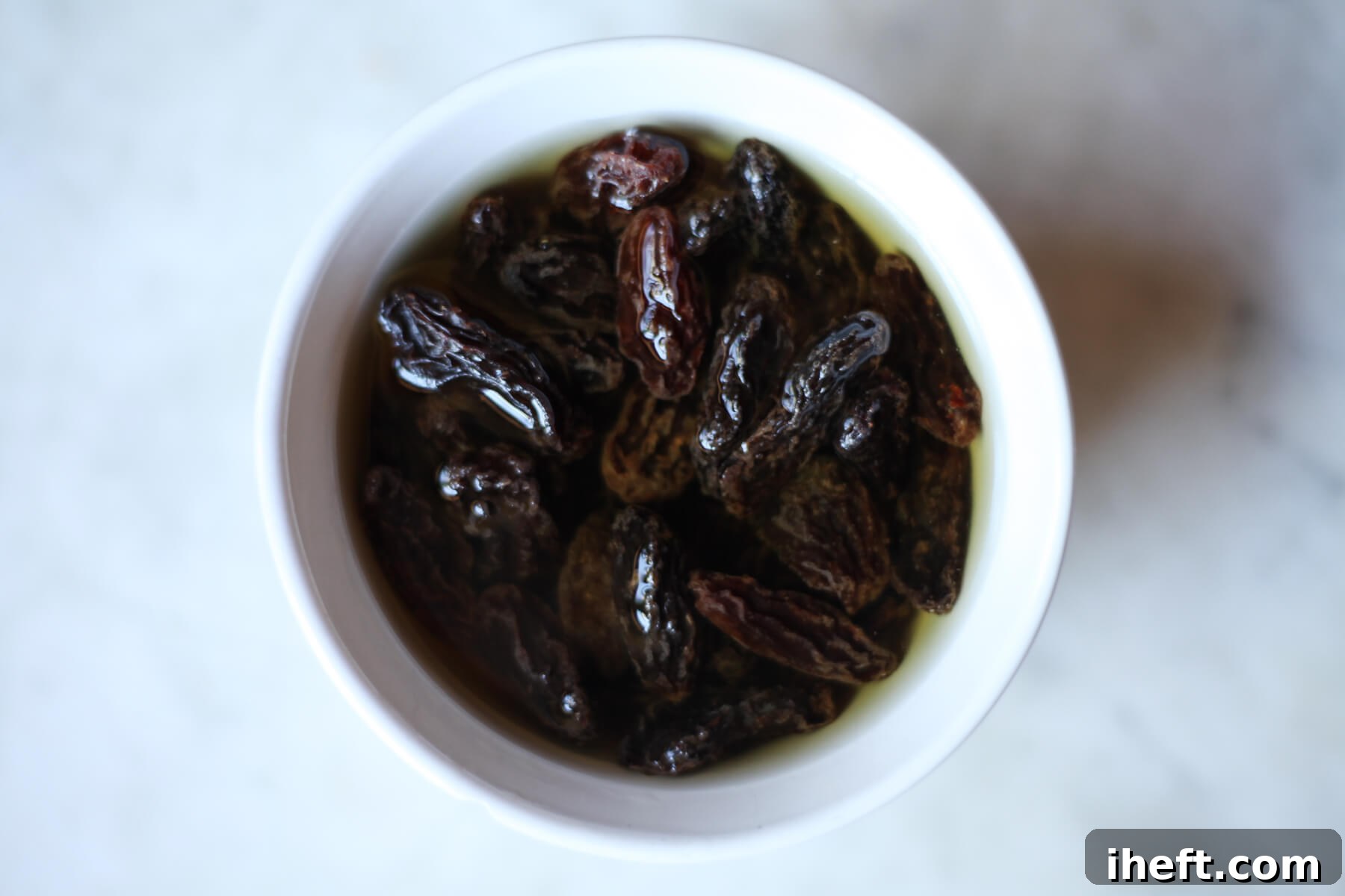 Rasins soak in a small bowl of brandy, becoming plump and juicy.