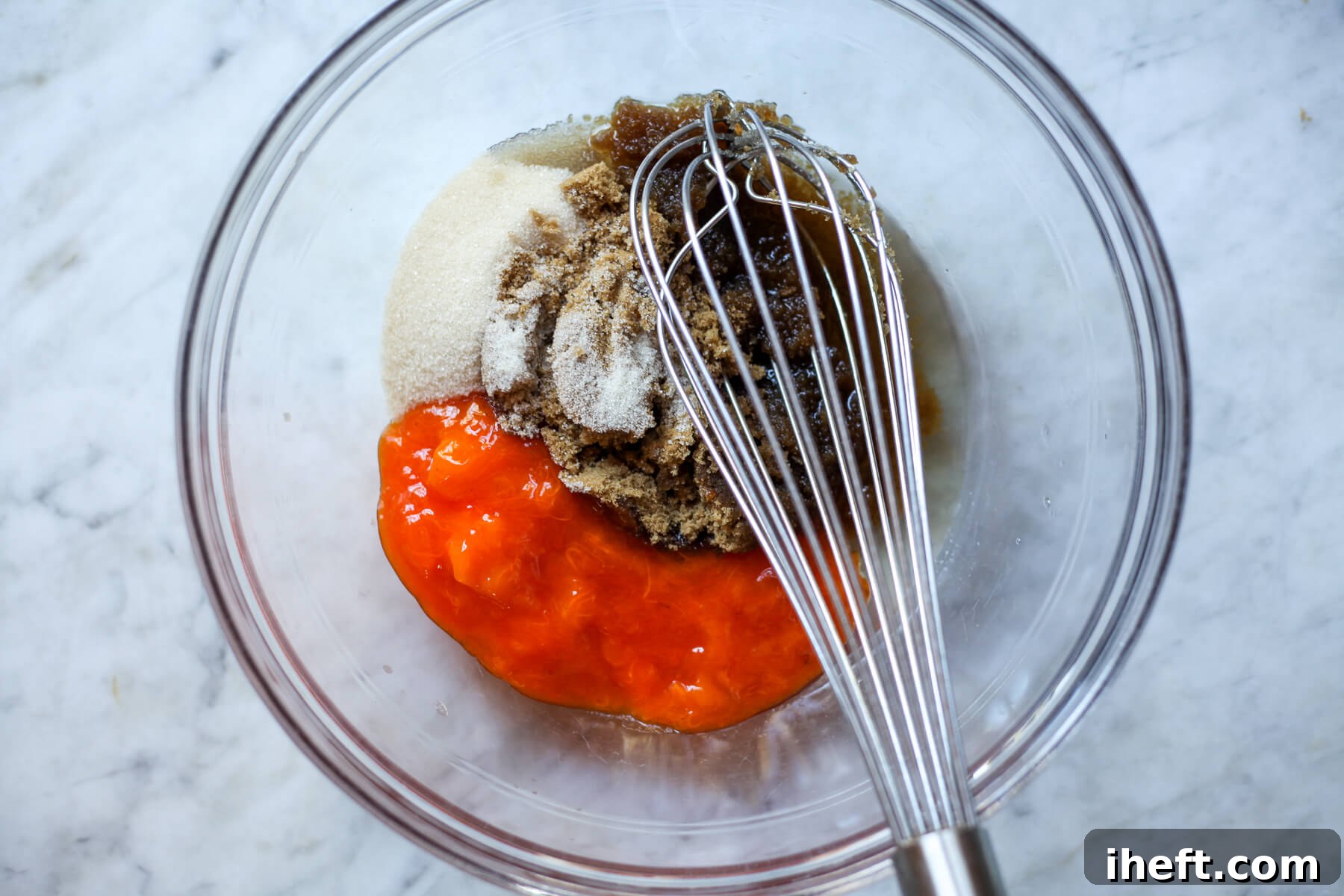 Persimmon pulp, sugars, and oil are vigorously whisked together in a clear glass bowl, forming the wet mixture.