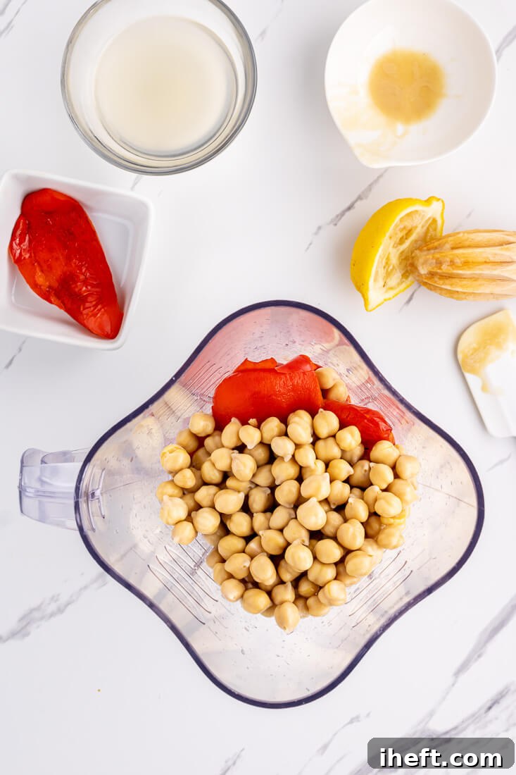 The ingredients for roasted red pepper hummus can be seen in a blender.