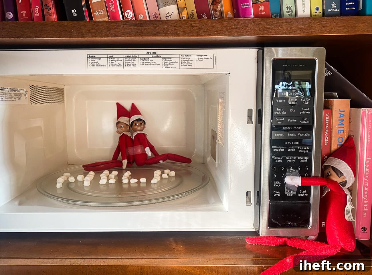 Two Elf on the Shelf dolls are tied up in a microwave while a third pretends to turn it on. A silly elf on the shelf idea. 