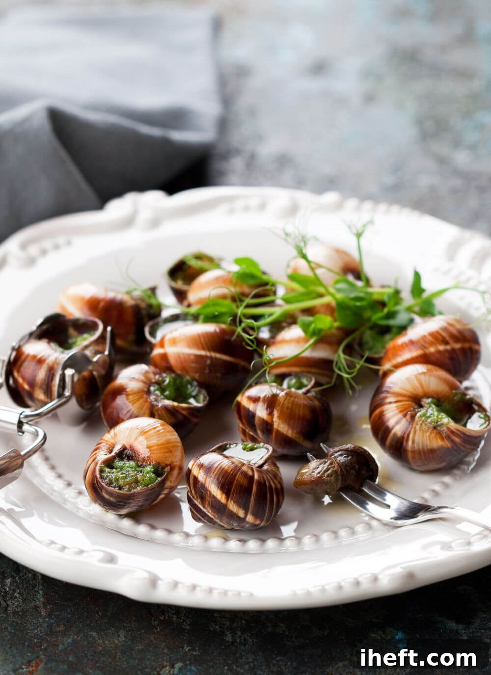 A beautifully plated dish of escargot, featuring snails nestled in their shells with a vibrant green garlic butter sauce, ready to be served.