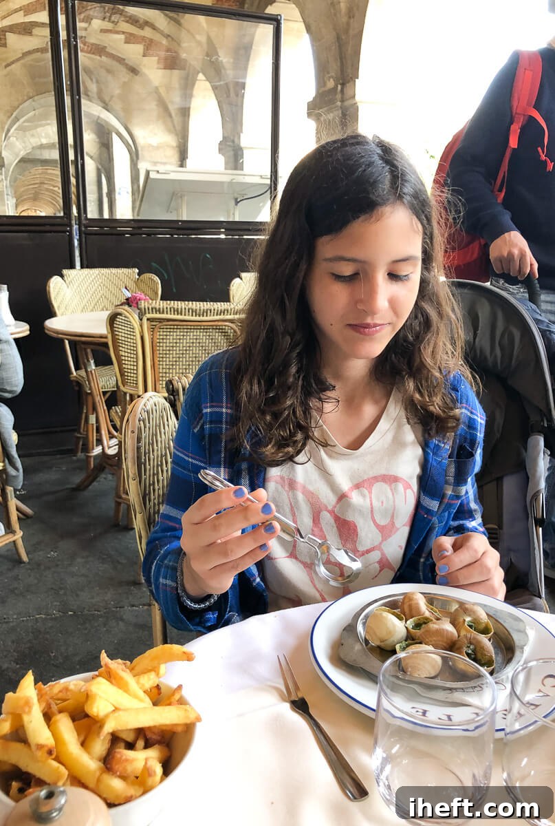 A young girl enjoys a plate of escargot served in their shells with crispy fries, capturing a classic Parisian cafe experience at Carette.