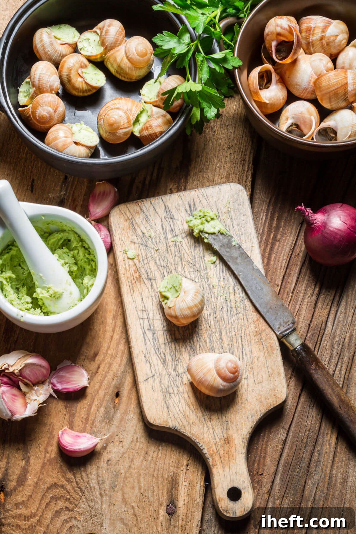 A rustic wooden table showcases the components and final dish of Escargots de Bourgogne, with bowls of empty snail shells, homemade vibrant parsley butter, and freshly prepared, bubbling escargots.