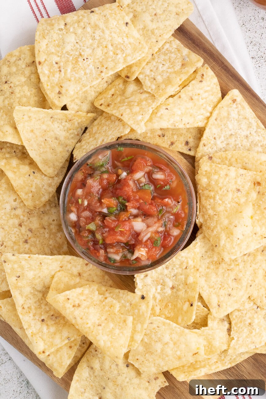 Homemade chunky red salsa in a bowl surrounded by chips.