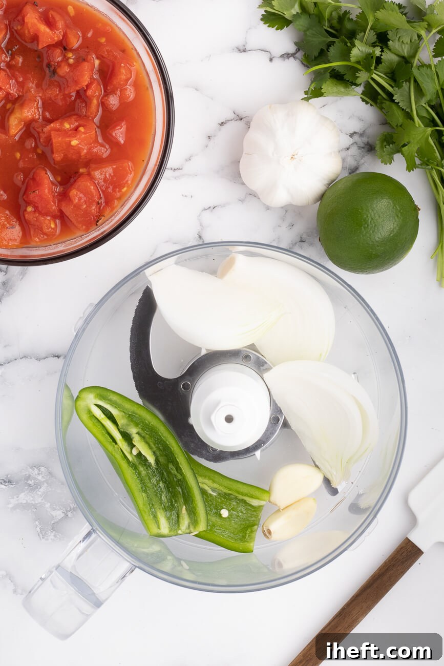Jalapenos, garlic, and white onion in the bowl of a food processor.