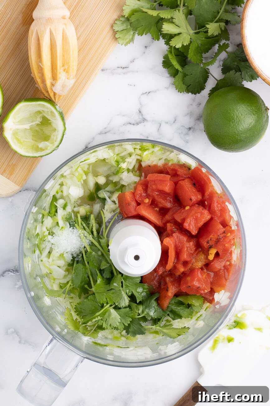 The ingredients for chunky homemade restaurant style salsa in the bowl of a food processor.