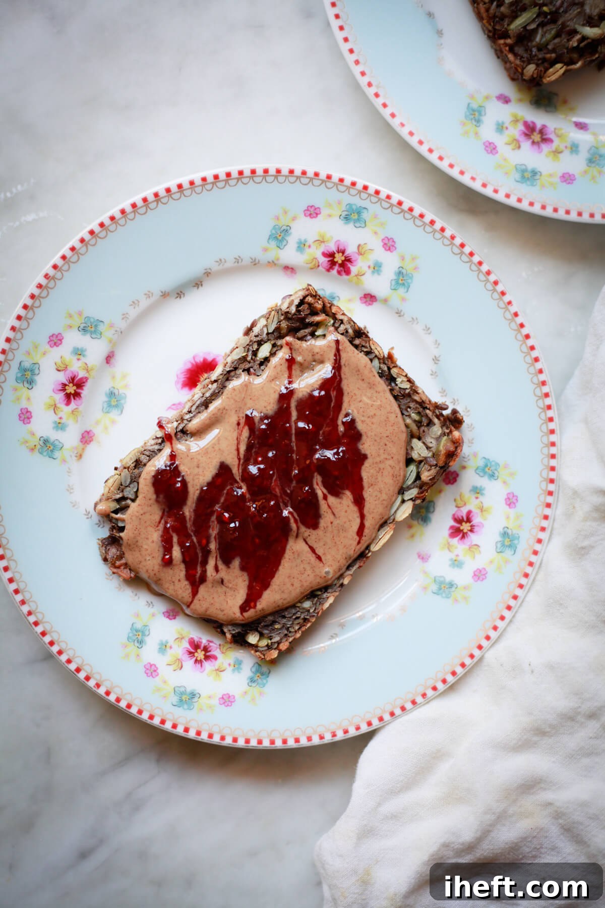 Seed bread slice topped with peanut butter and jam.