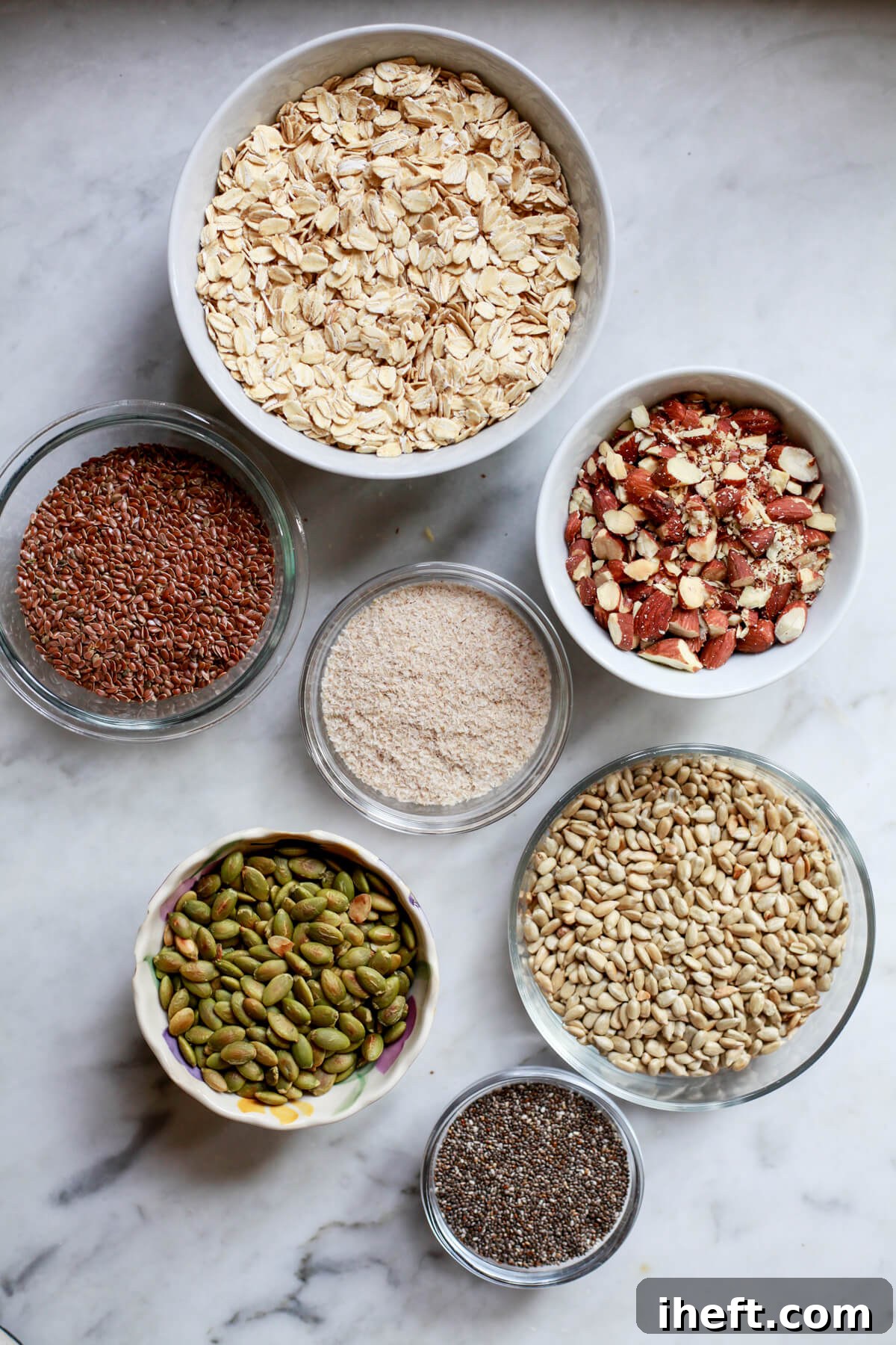 Various bowls holding the essential ingredients for gluten-free super seed bread, neatly arranged. This vibrant collection includes golden oats, slivered almonds, fluffy psyllium husks, rich flax seeds, bright sunflower seeds, dark pumpkin seeds, and tiny chia seeds, showcasing the wholesome components. 