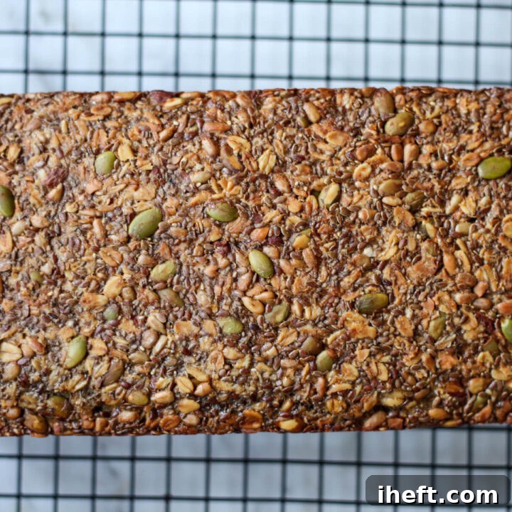 A loaf of homemade gluten-free adventure seed bread on a wire cooling rack.