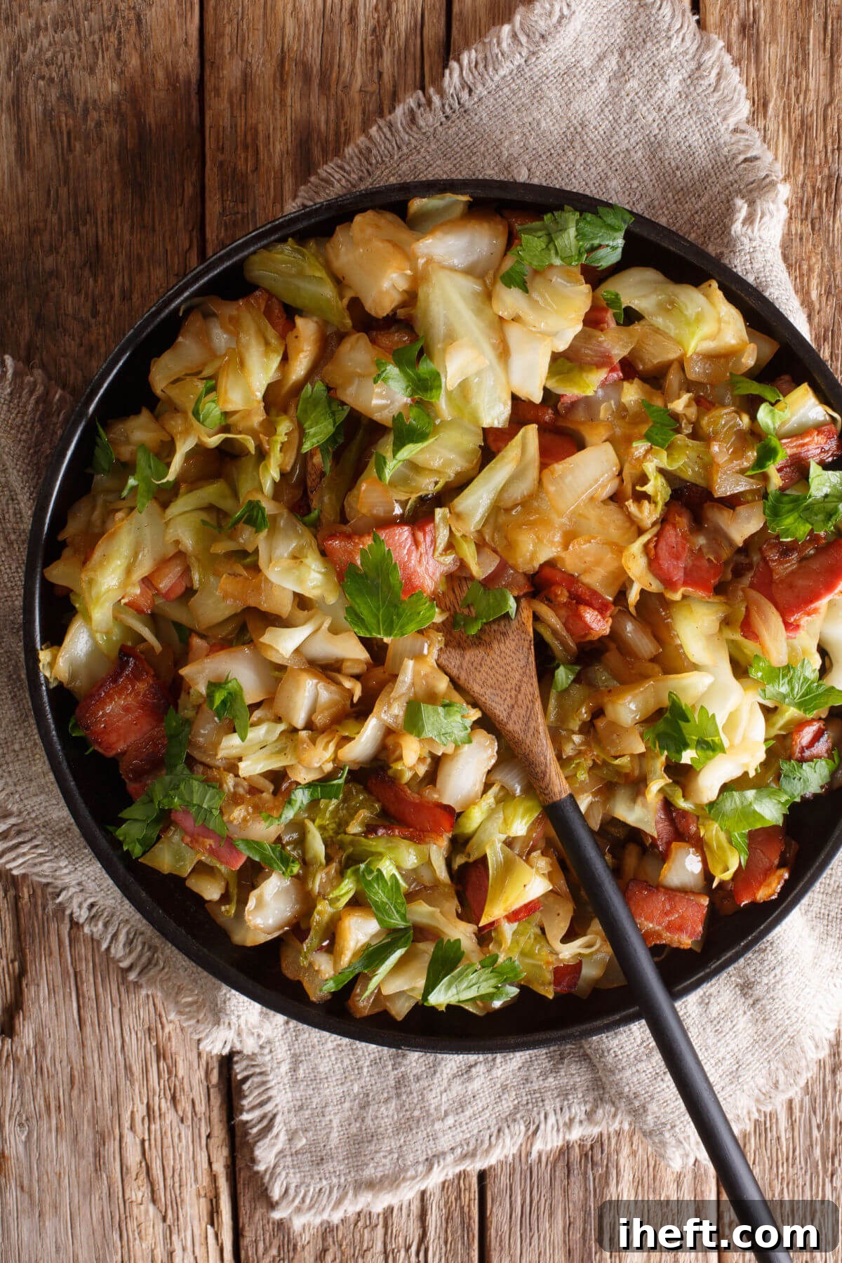 A dark round dish filled with perfectly cooked cabbage and savory bacon, elegantly garnished with fresh parsley. This classic dish represents a typical and beloved Irish food. 