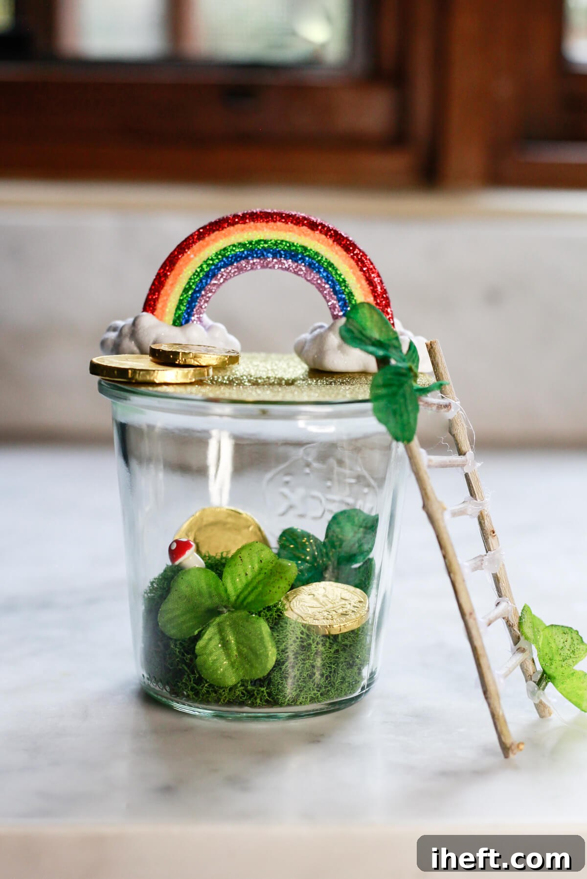 A cute and simple leprechaun trap made with a canning jar, moss, gold coins, rainbow, and ladder. 