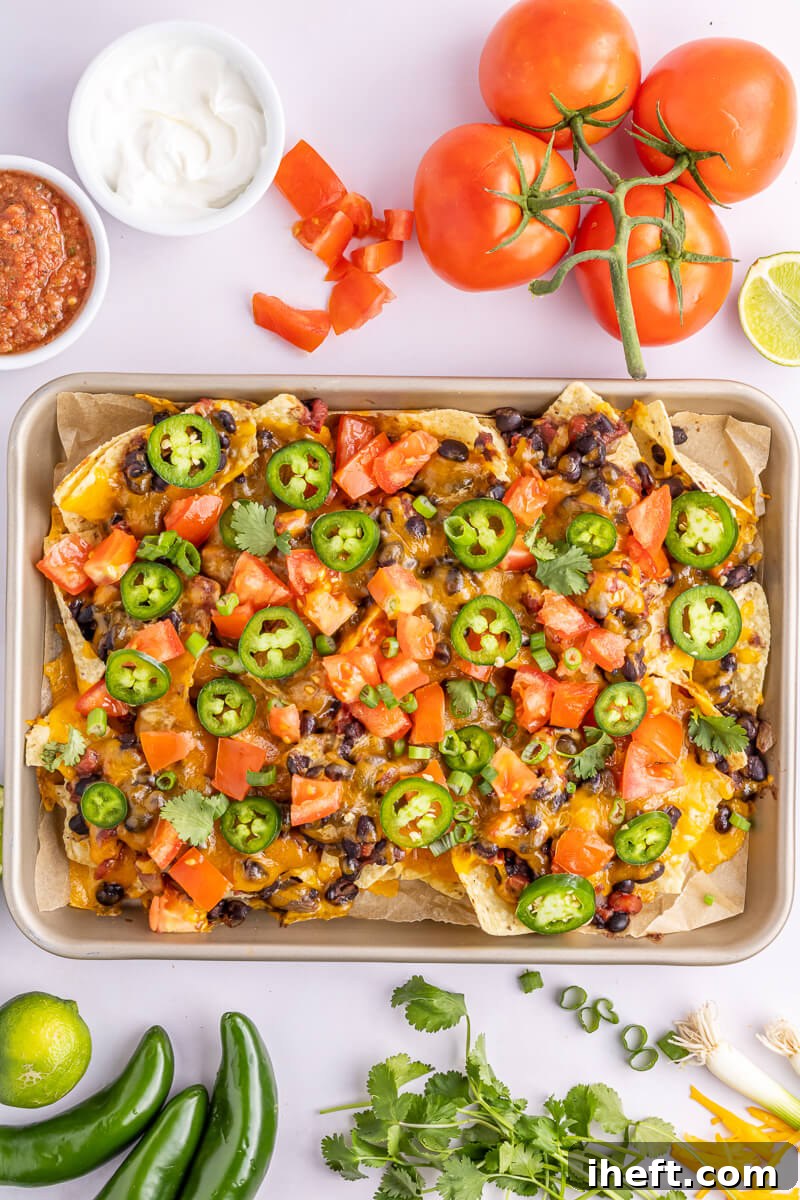 Sheet pan vegetarian nachos topped with jalapeno and tomato.