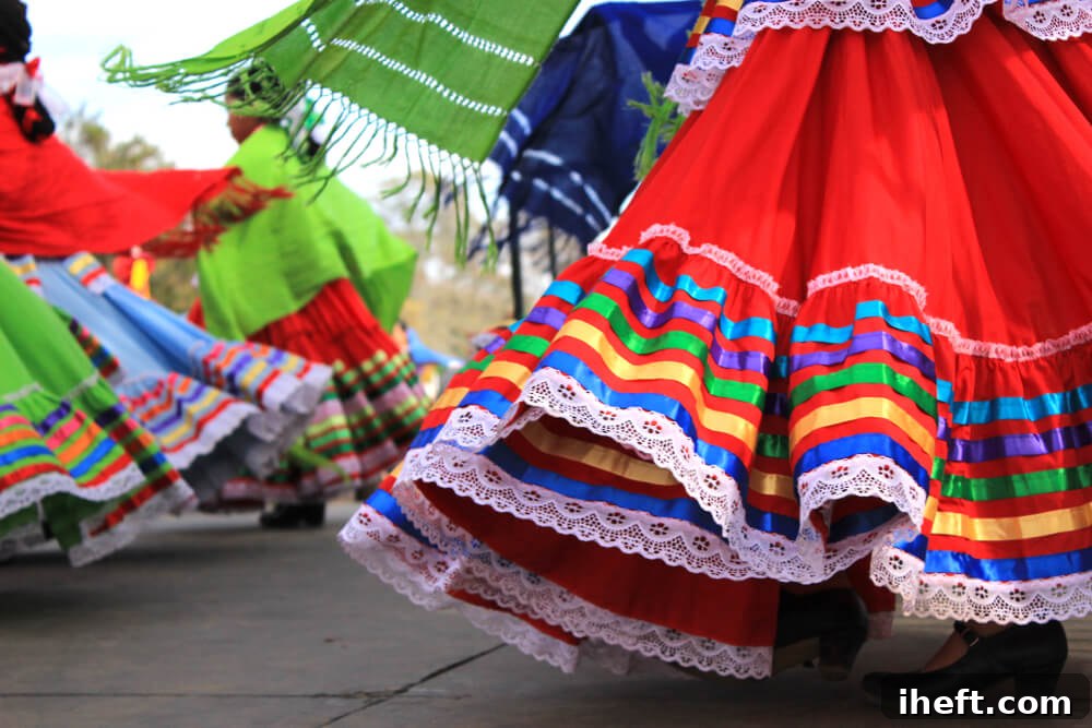 Traditional Mexican dresses swing on dancers. These dresses are in Traditional Mexican colors: red, green, white, and blue. 