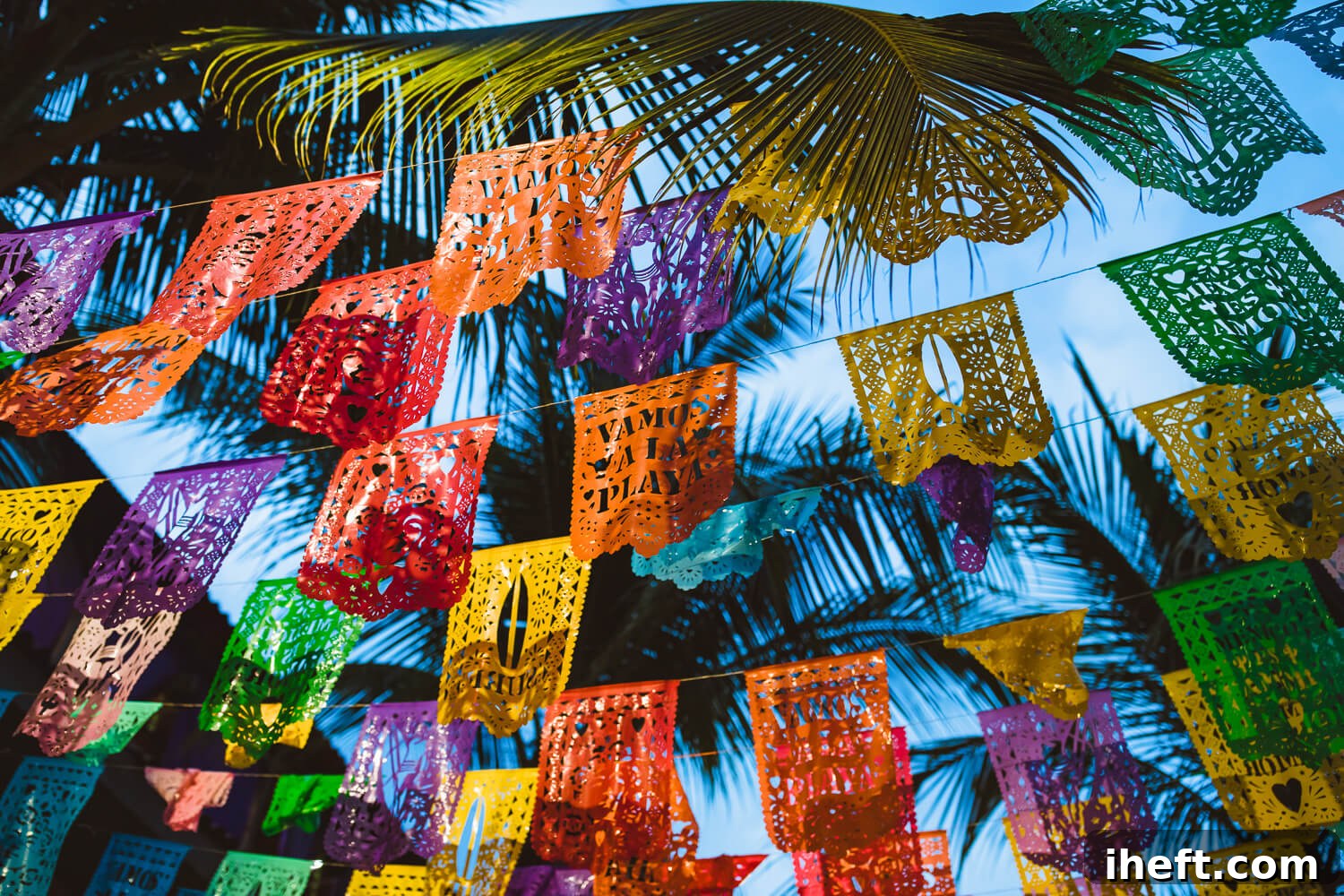 Colorful Mexican flag decorations hung from trees in Sayulita, Mexico. Red, orange, yellow, green, and purple paper flags. These are bright Mexican colors perfect for celebrations like Cinco de Mayo. 