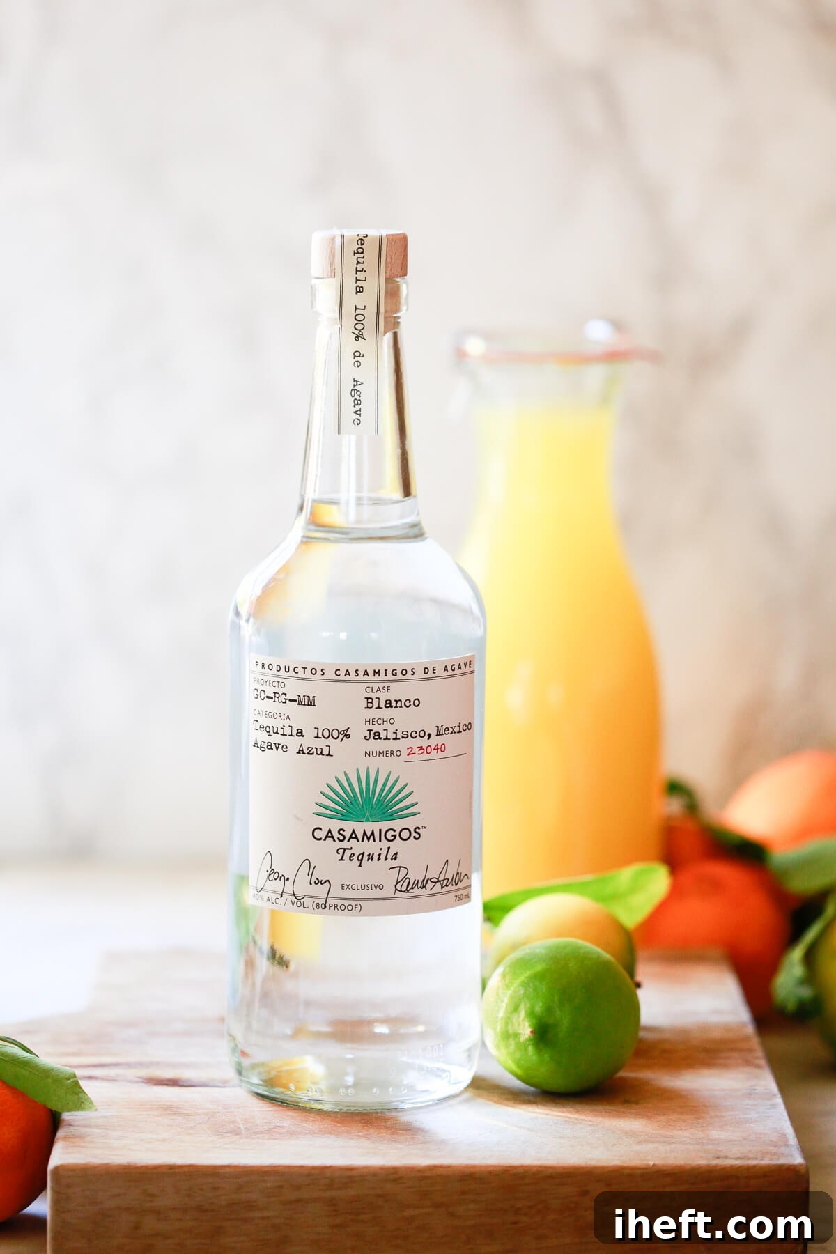 A bottle of Casamigos tequila in the foreground with a jug of homemade yellow margarita mix in the background. 