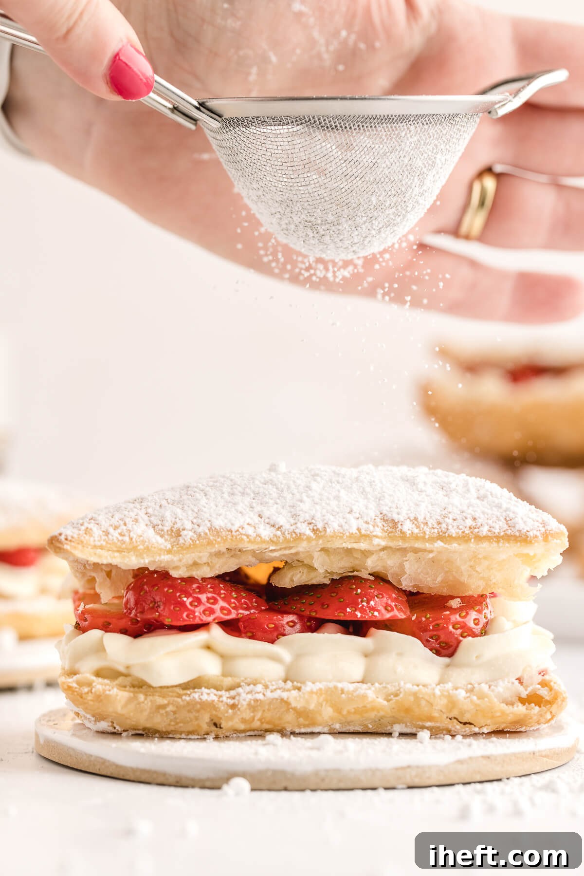 A single Napoleon dessert (strawberry Mille-Feuille) is dusted with powdered sugar. 
