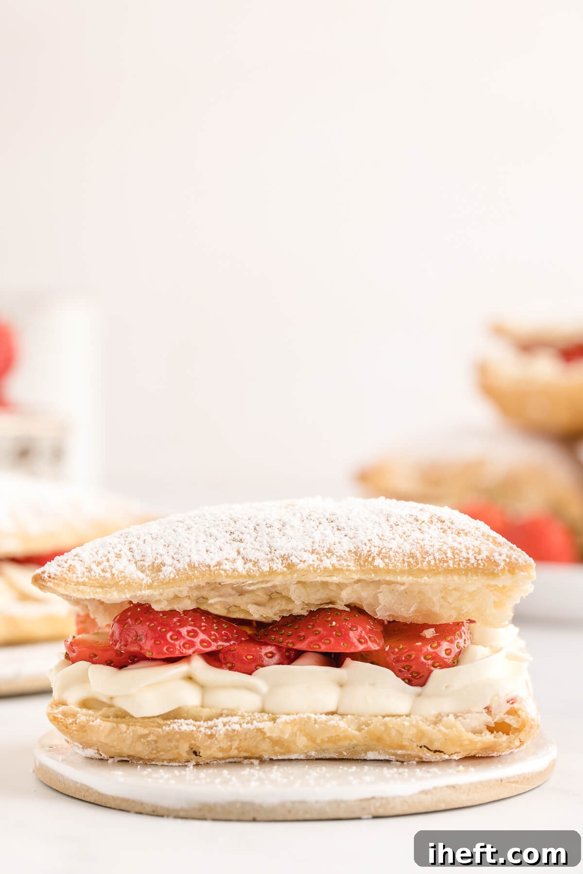A beautiful Mille-Feuille Napoleon dessert made with layers of puff pastry, strawberries, and whipped cream dusted with powdered sugar. 