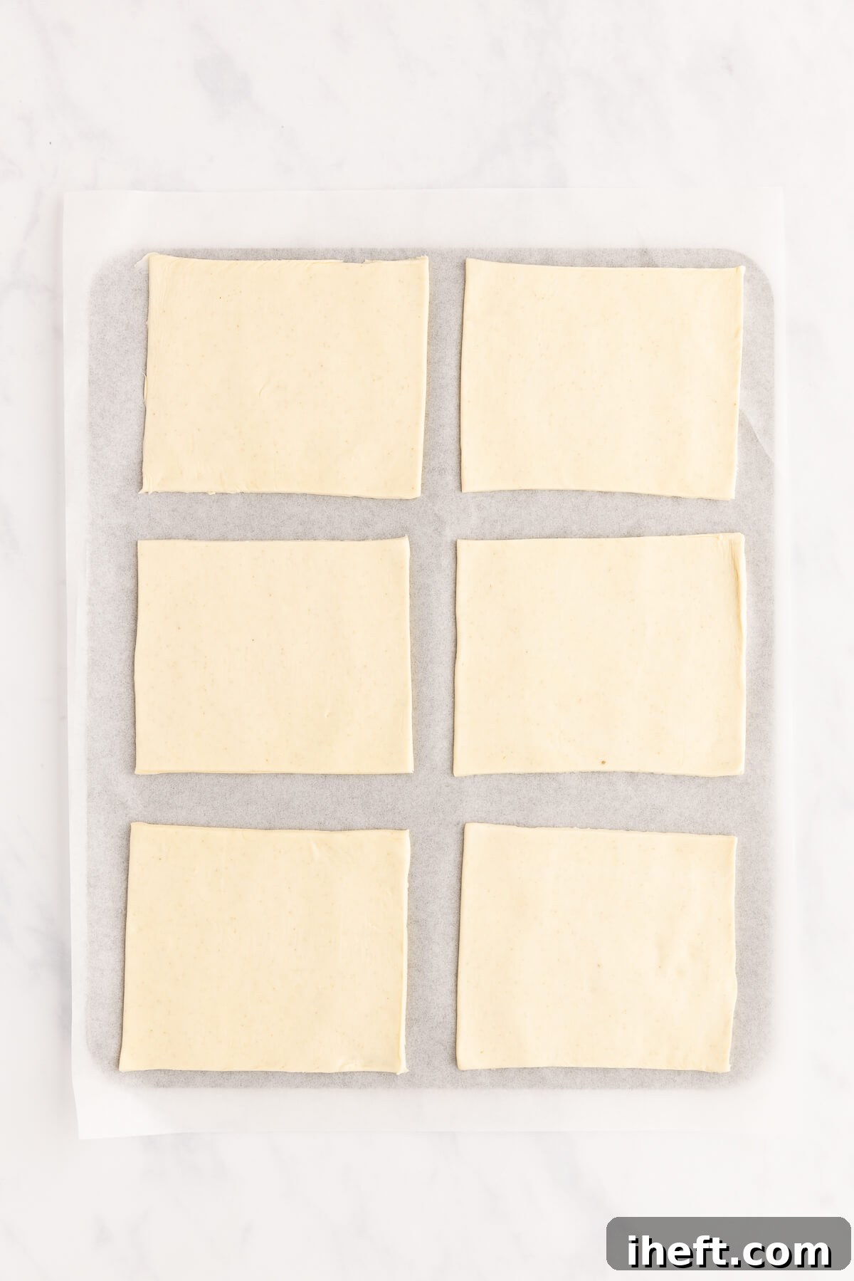 6 pieces of puff pastry on a parchment lined baking sheet.