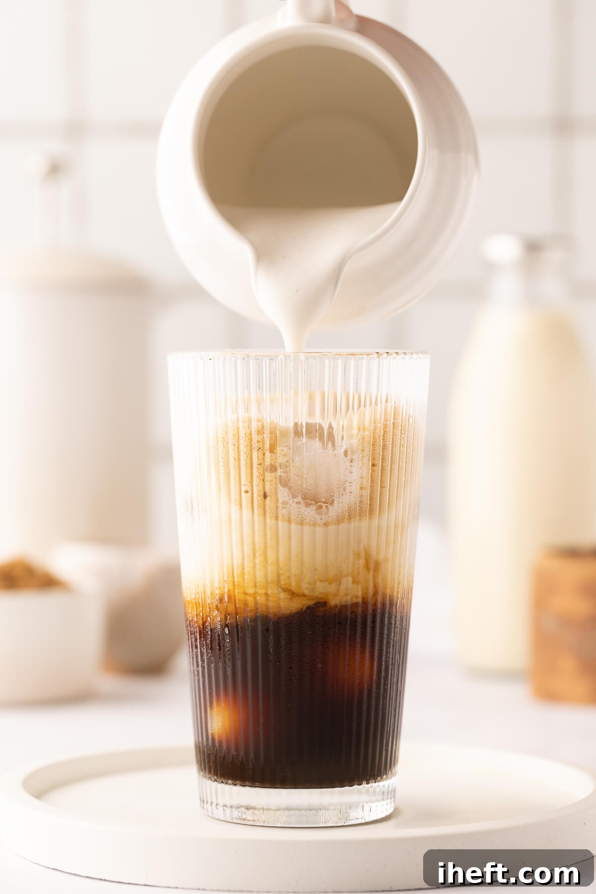 Frothy oatmilk is poured over a brown sugar shaken espresso.