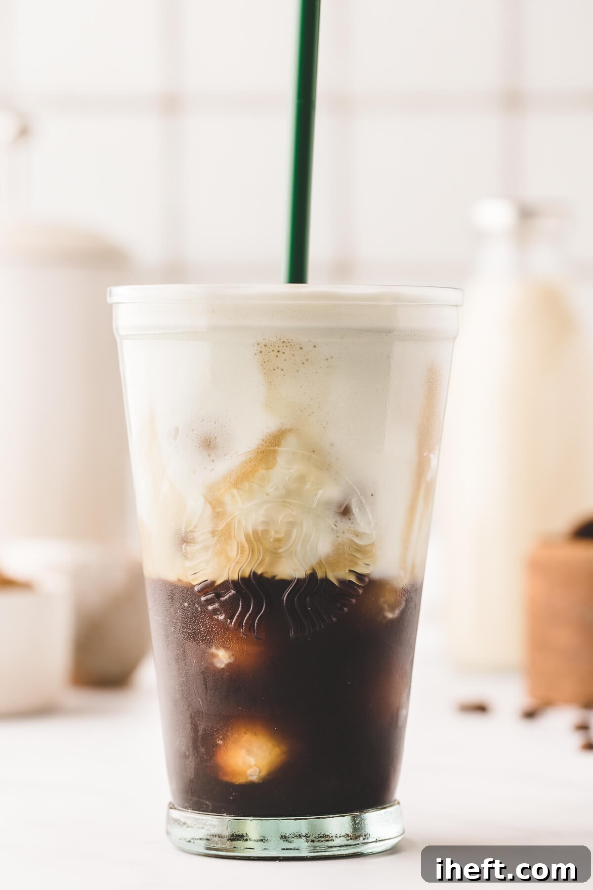 A brown sugar oatmilk shaken espresso in a Starbucks glass with ice and a green straw. 