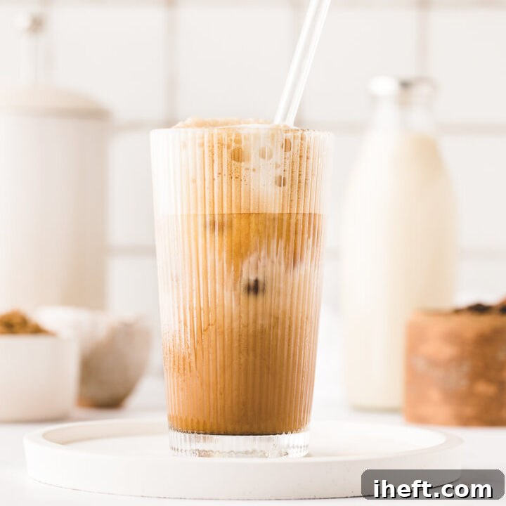 A homemade brown sugar oat milk shaken espresso drink sits on a white kitchen counter.