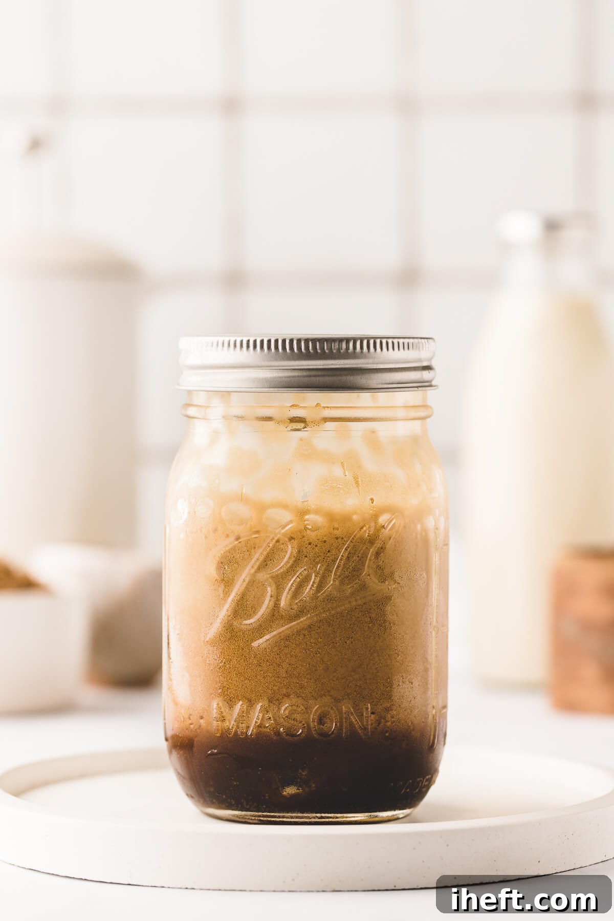 A Ball mason jar with a lid on filled with shaken espresso.