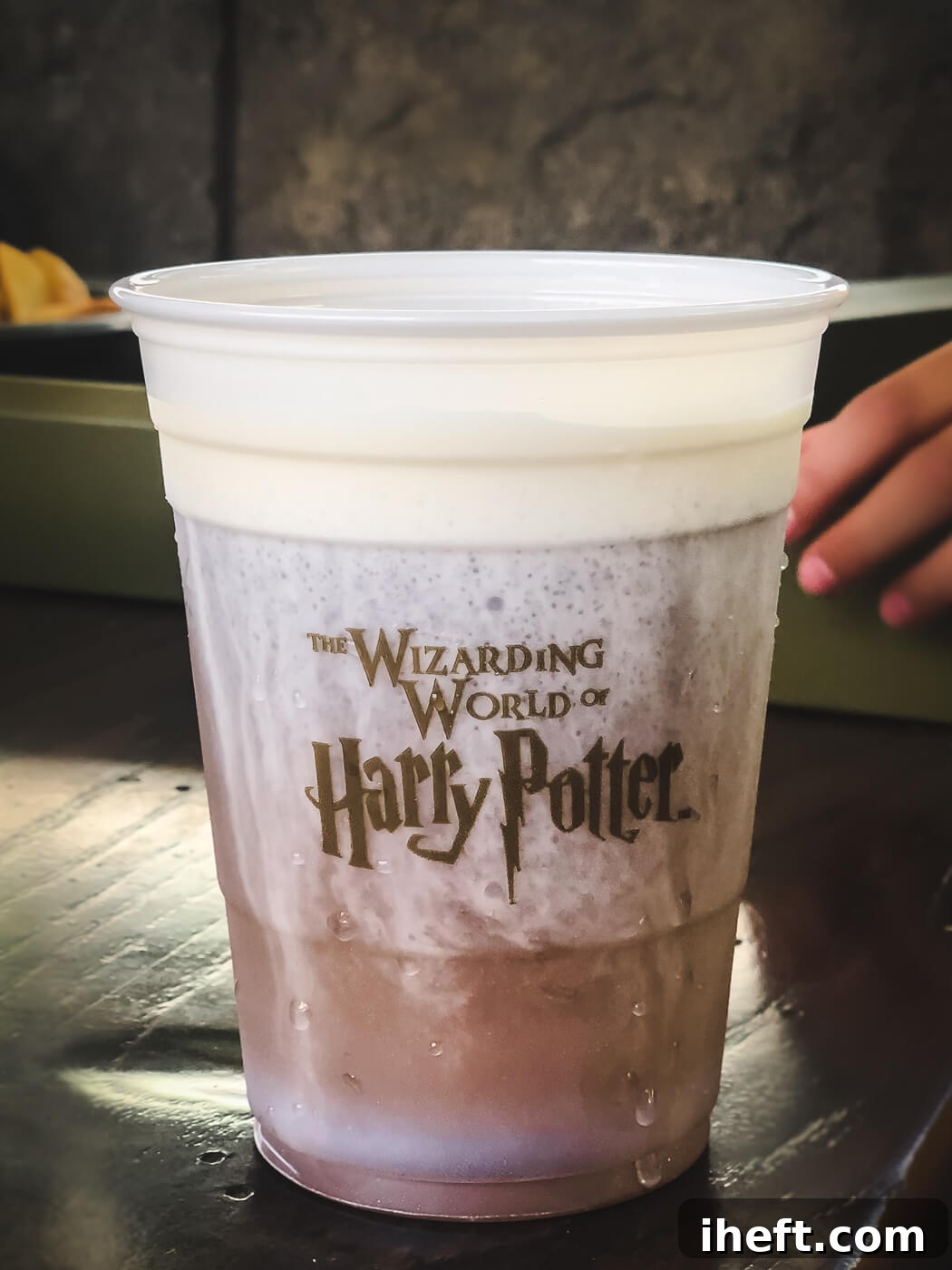 A frothy cup of golden Butterbeer, featuring "The Wizarding World of Harry Potter" emblem, ready to be enjoyed at Universal Studios.