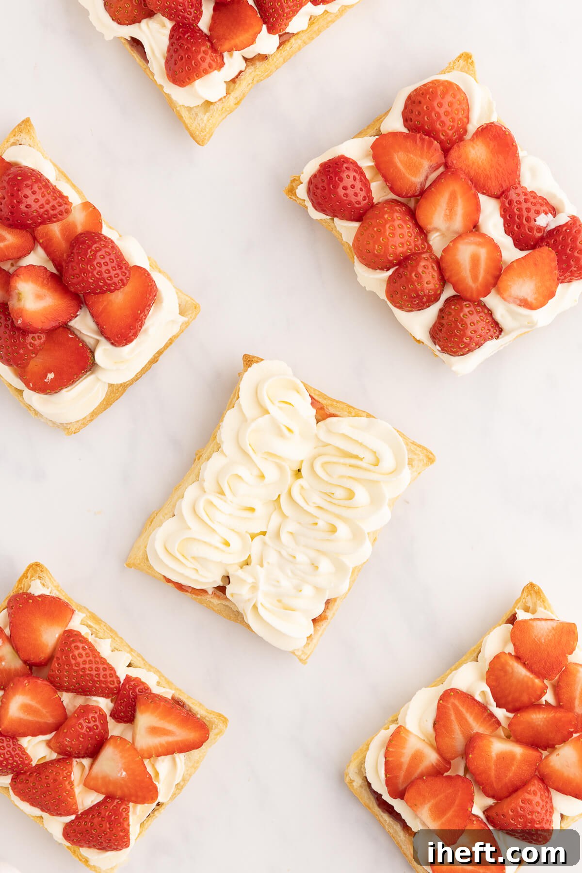 An inviting image of puff pastry squares generously topped with fluffy whipped cream and vibrant fresh strawberries, arranged as a fancy dessert that is both visually appealing and delicious.