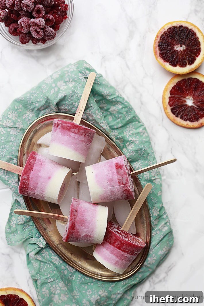 Close-up view of two ombré berry yogurt ice pops, showcasing layers of different pink and purple hues from berries and yogurt, presented as a healthy and fun frozen treat.