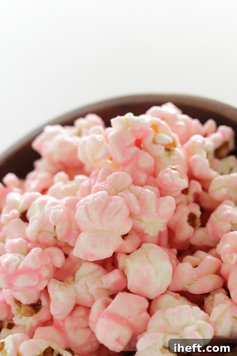 A large bowl overflowing with vibrant pink coated popcorn, ready to be enjoyed as a fun and festive snack.