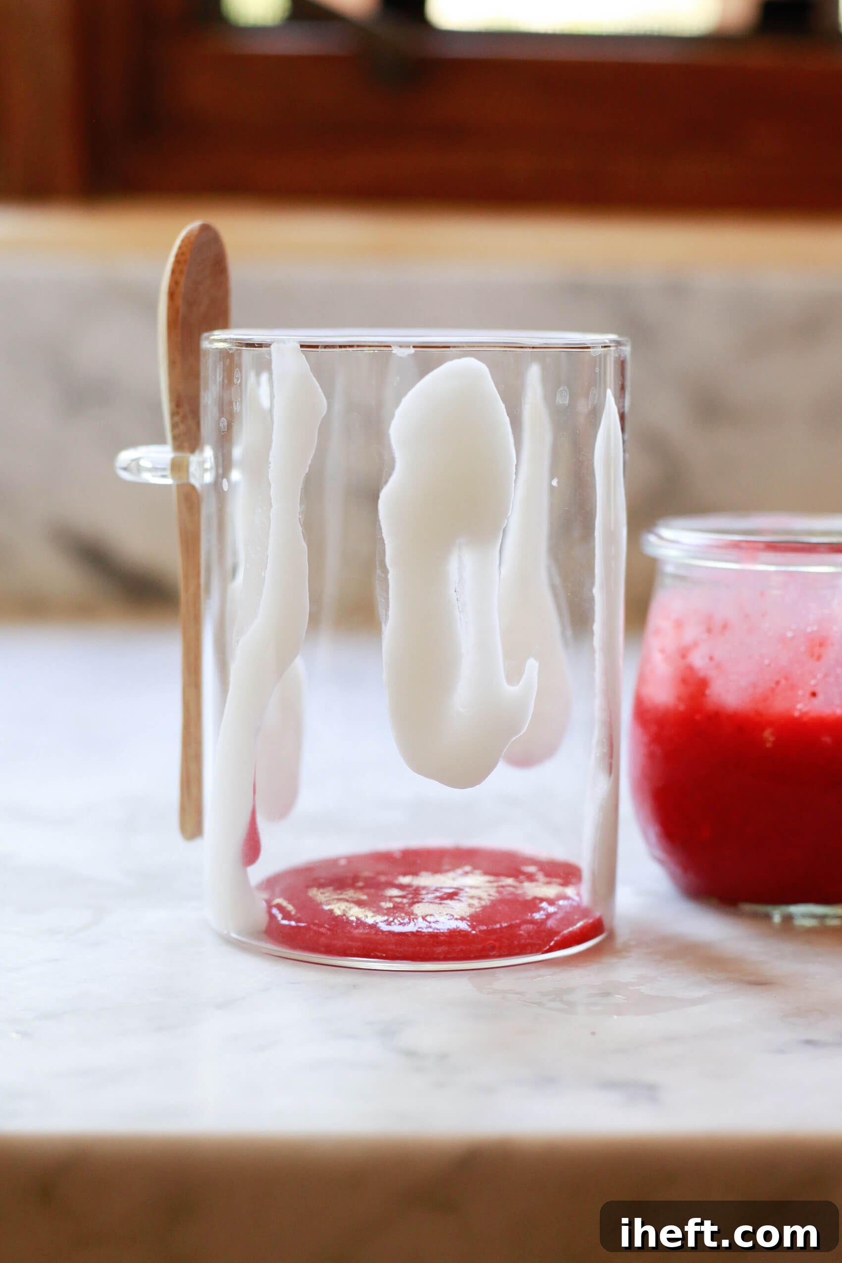 How to make Hailey Bieber smoothie with strawberry glaze and coconut cream. Coconut cream lines in a glass with strawberry glaze at the bottom.
