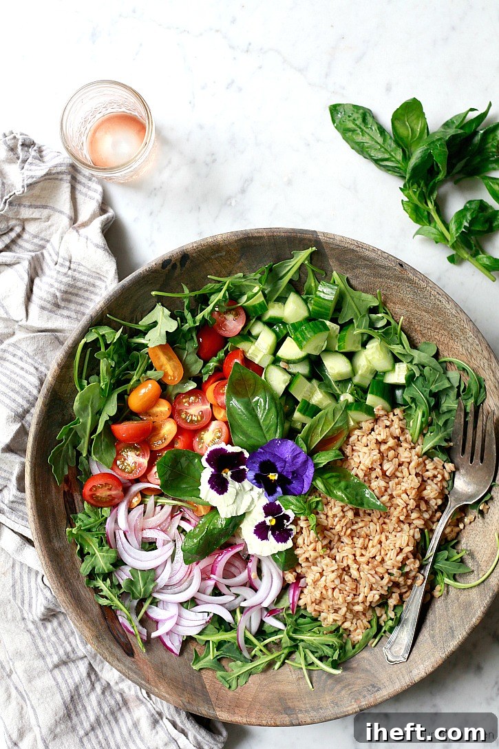 A vibrant Italian farro salad bowl featuring healthy ingredients like peppery arugula, ripe tomatoes, crisp red onions, refreshing cucumber, and savory olives.