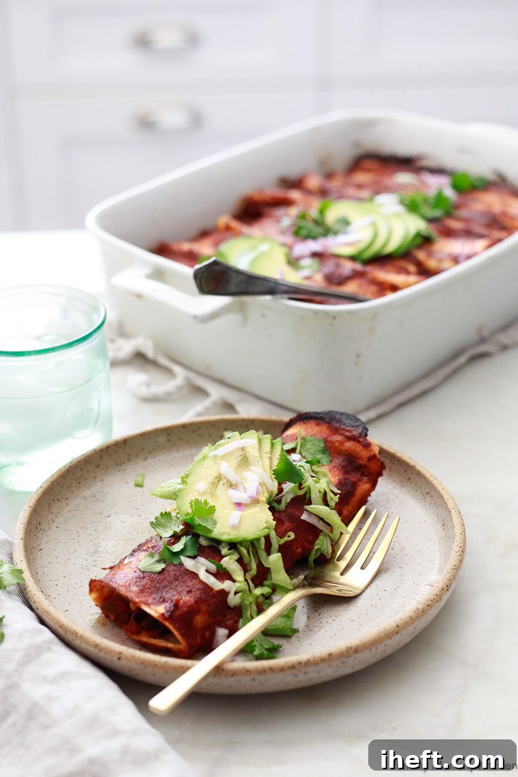 Freshly baked vegetarian enchiladas, filled with a savory mix of black beans and corn, presented in a bright white kitchen setting. This image emphasizes the homemade, wholesome appeal of the enchiladas.