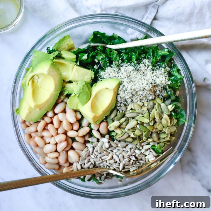 An overhead photo of a white bean kale salad with avocado, sunflower seeds, hemp seeds, and pepitas.