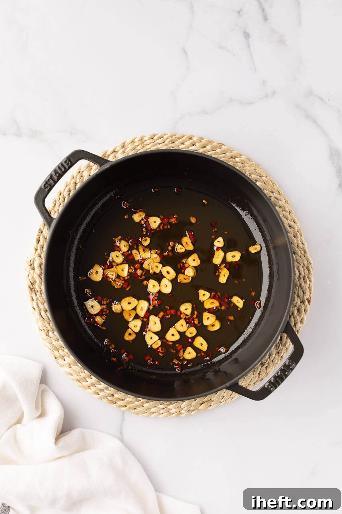 Sliced garlic and peperoncino chili peppers in olive oil in a pan.