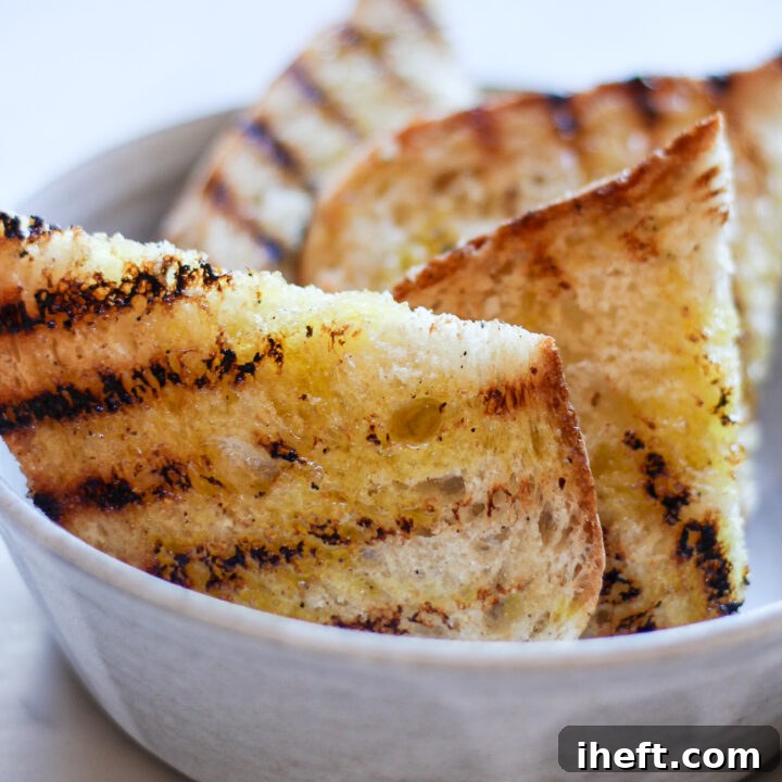 Grilled Italian fettunta bruschetta halves with olive oil in a grey ceramic bowl.