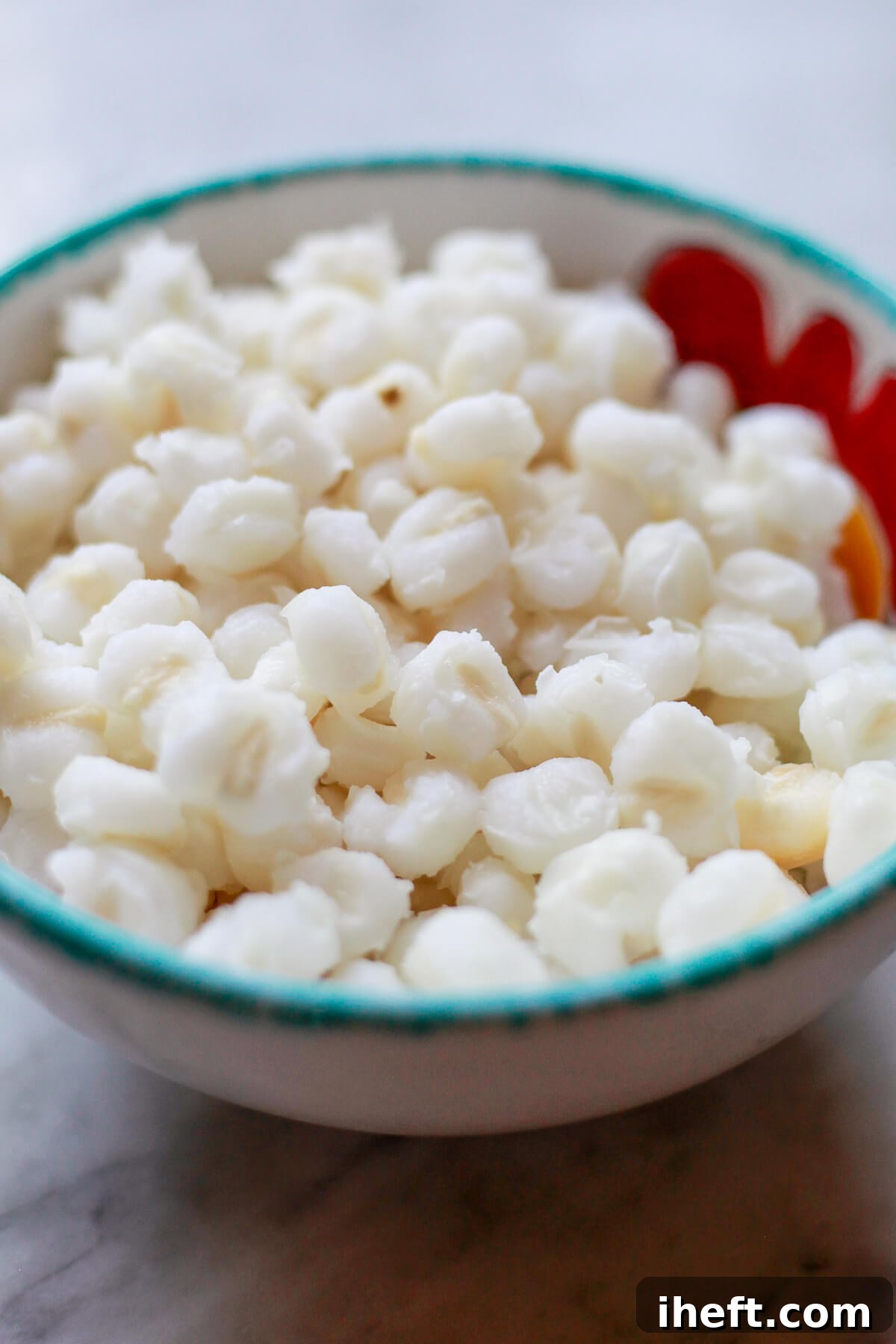 Cooked white hominy in a ceramic bowl with a turquoise rim.