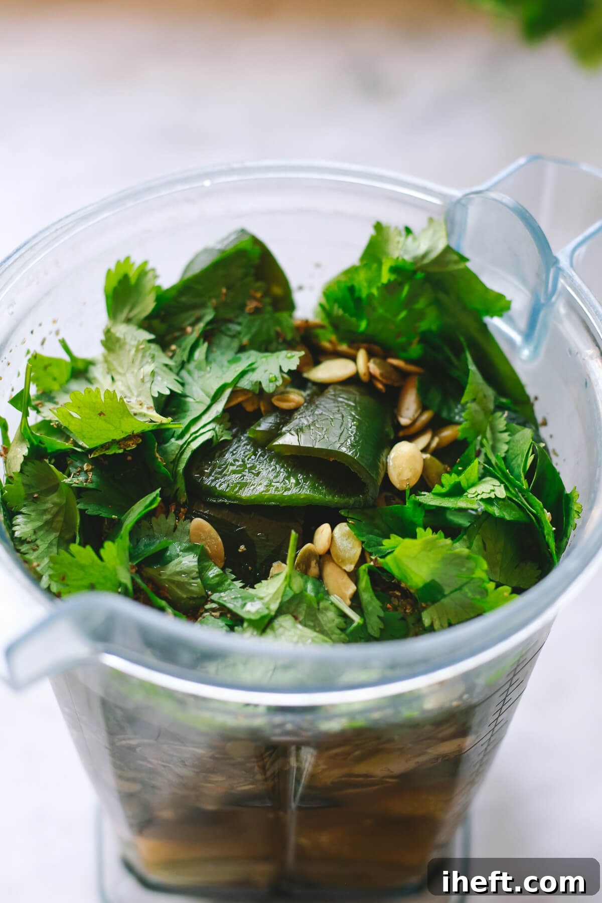 The ingredients for pozole verde in a Vitamix blender. Poblano peppers, pepitas, and cilantro can be seen.