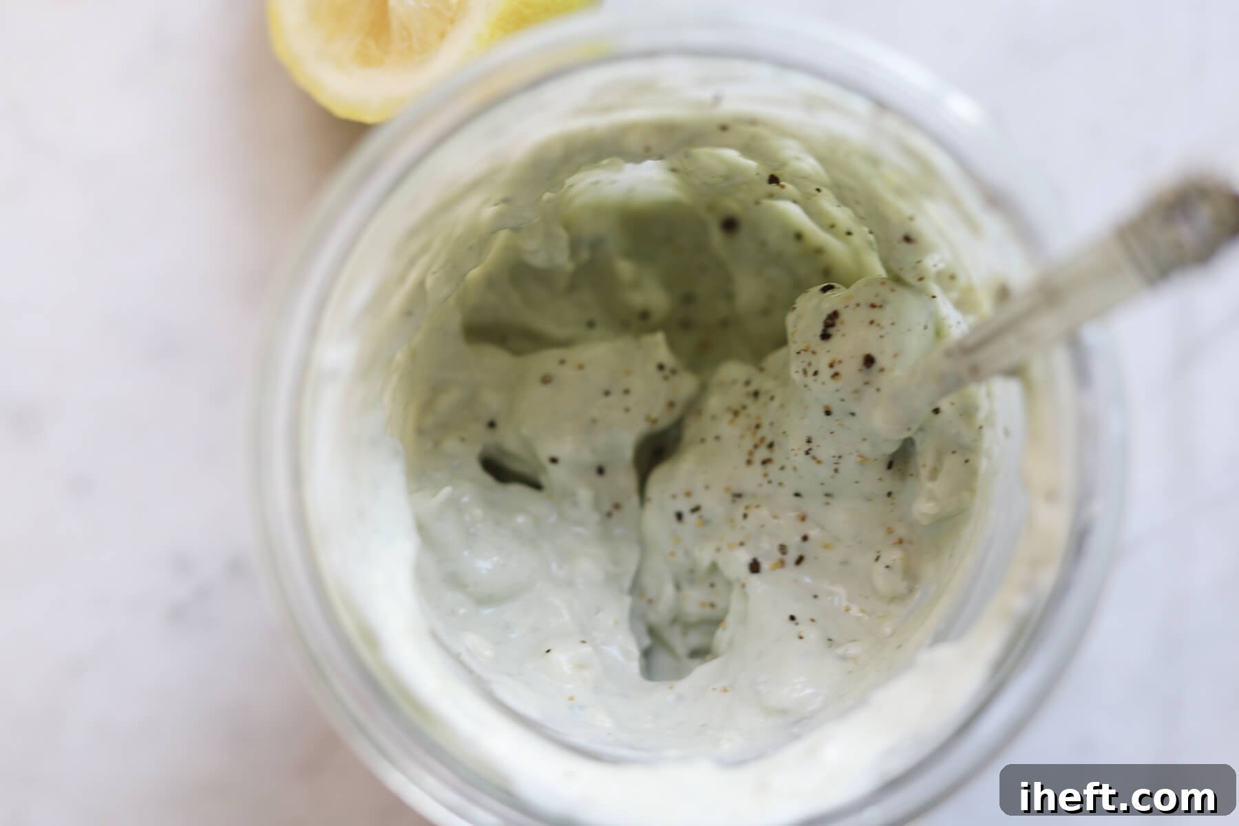 Homemade Roquefort dressing in a glass jar being seasoned with salt and pepper.