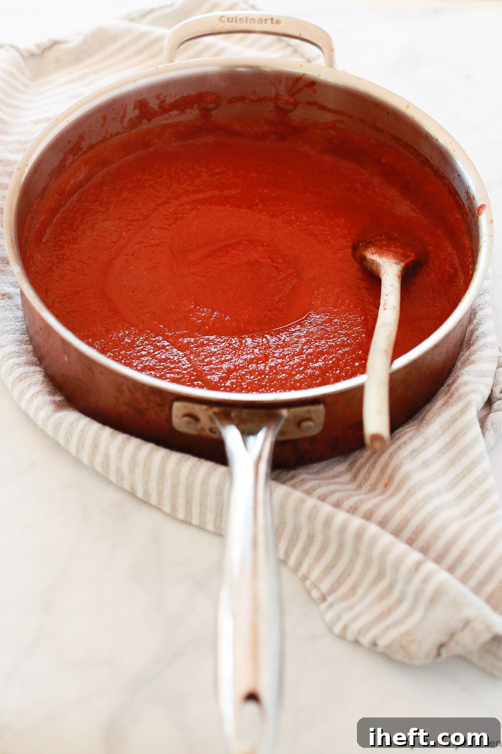 A large saucepan filled with vibrant homemade red enchilada sauce, freshly blended and ready to simmer on the stove.