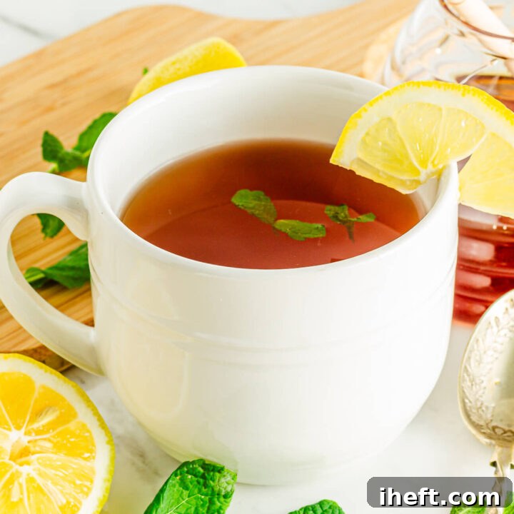 A white mug filled with a copycat Starbucks medicine ball. The drink is garnished with a lemon slice and mint.