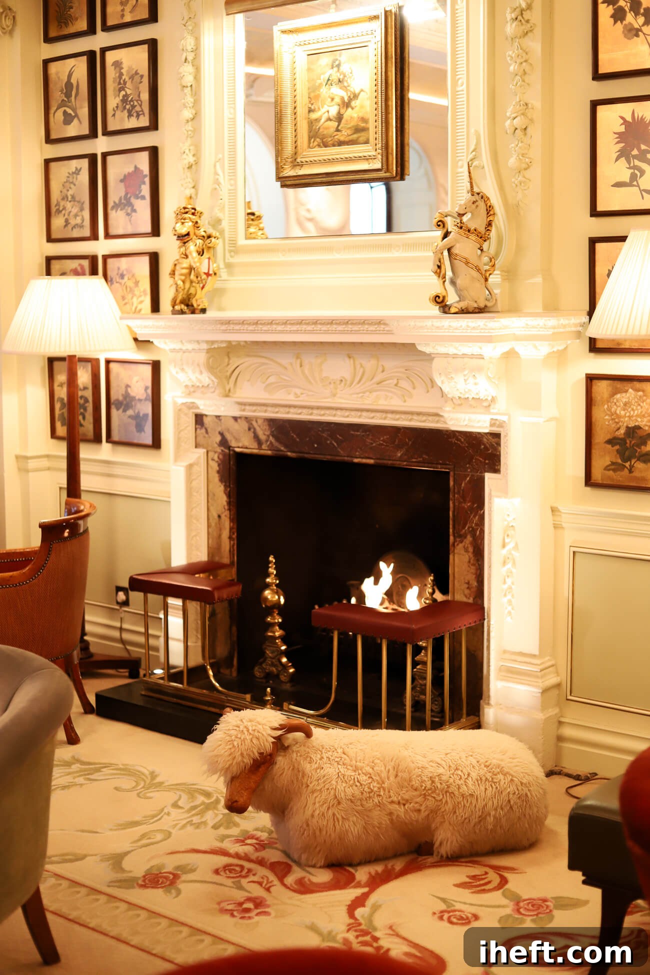 A white fluffy faux sheep with wood face and horns sits in front of a fireplace in the Goring bar lounge. 