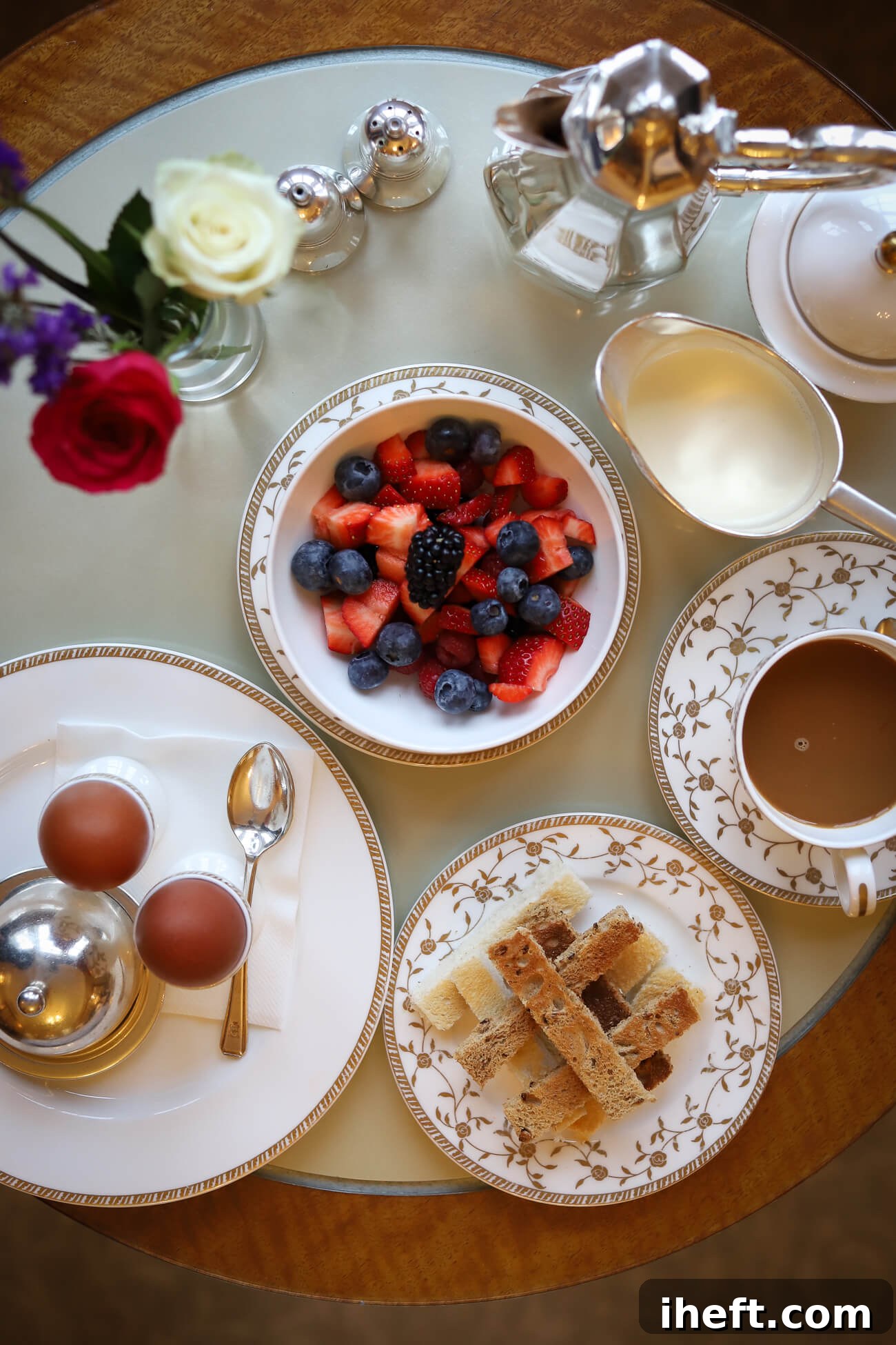 An overhead photo of a room service breakfast at the Goring. This includes a silver pot of coffee, two boiled eggs with toast "soldiers" and a bowl of berries on a round table. 