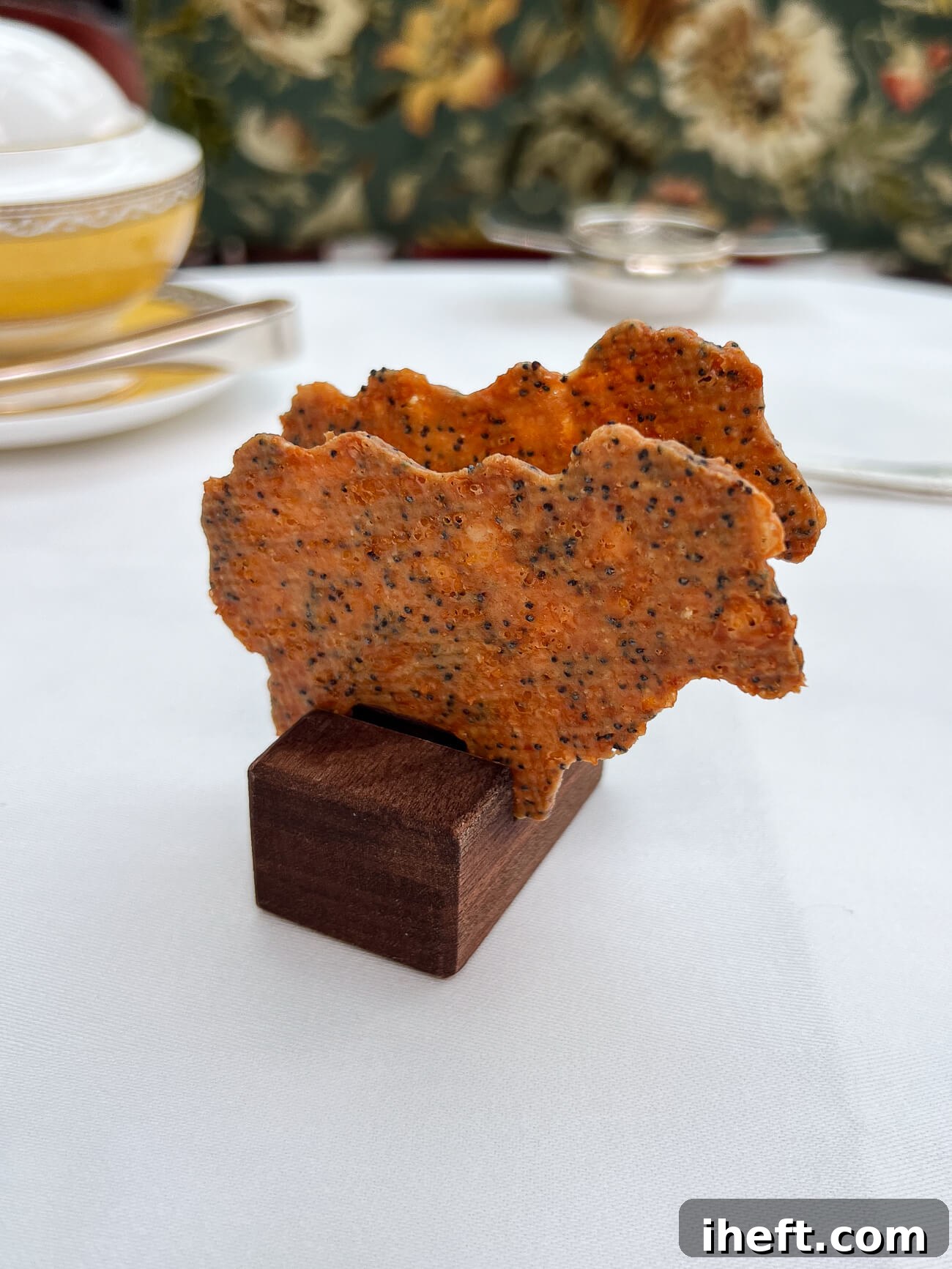 Two intricately shaped parmesan crisp crackers, designed like charming sheep, delicately presented on a rustic wooden block on the table during afternoon tea at The Goring Hotel in London, highlighting the unique and delightful touches of this luxury experience.
