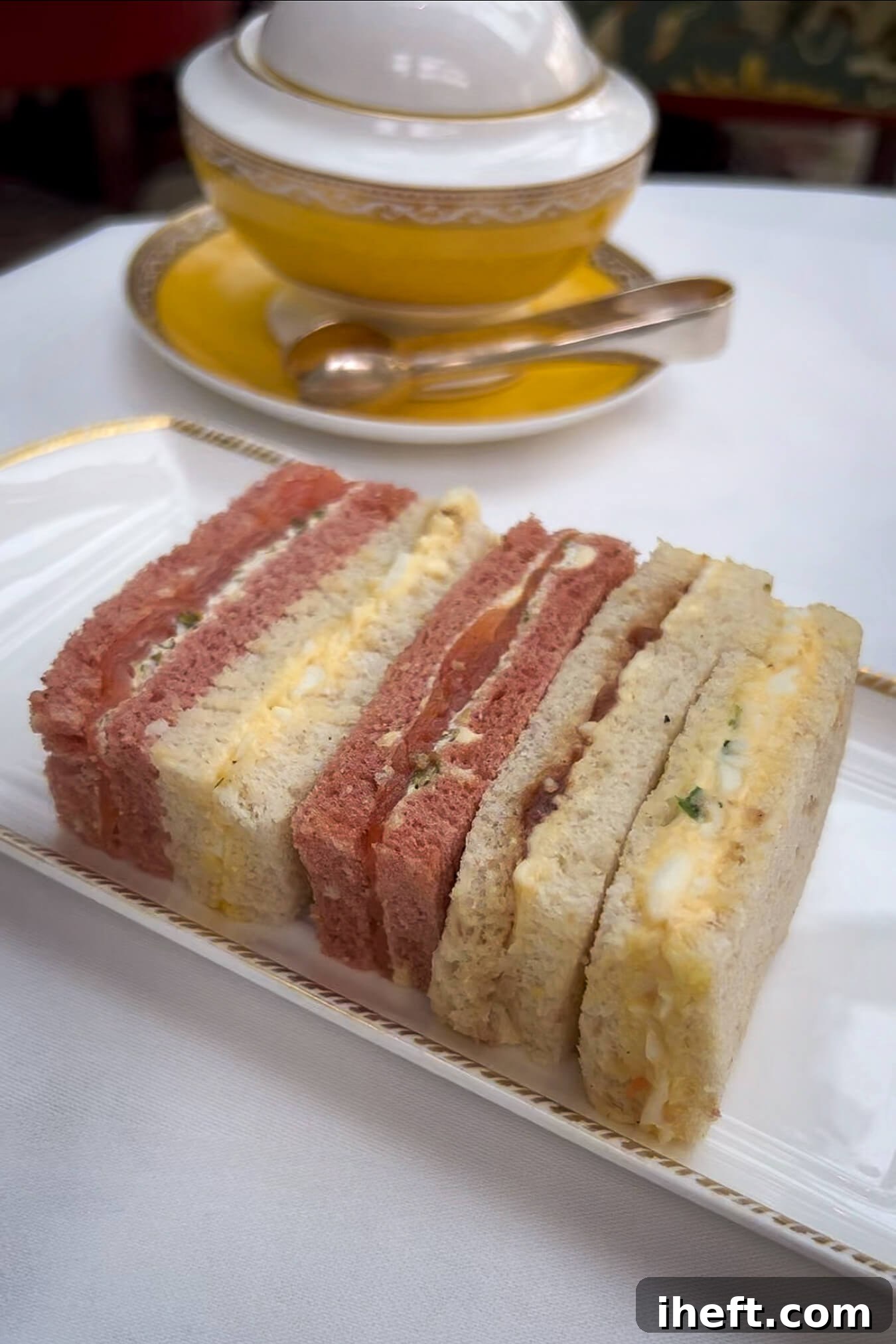 An elegant selection of perfectly cut finger sandwiches artfully arranged on a pristine white plate, served during the afternoon tea experience at The Goring Hotel in London, exemplifying why it's considered the best afternoon tea in the city.