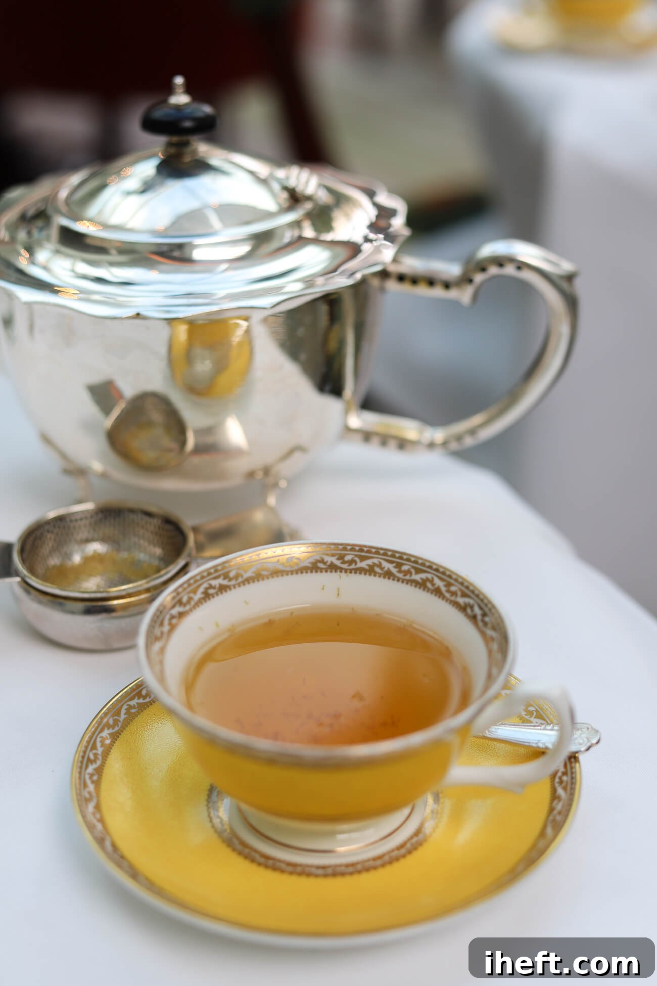 A beautifully set table for tea time, featuring a teapot, delicate teacups, and fresh flowers, inviting guests to a relaxing British tradition.