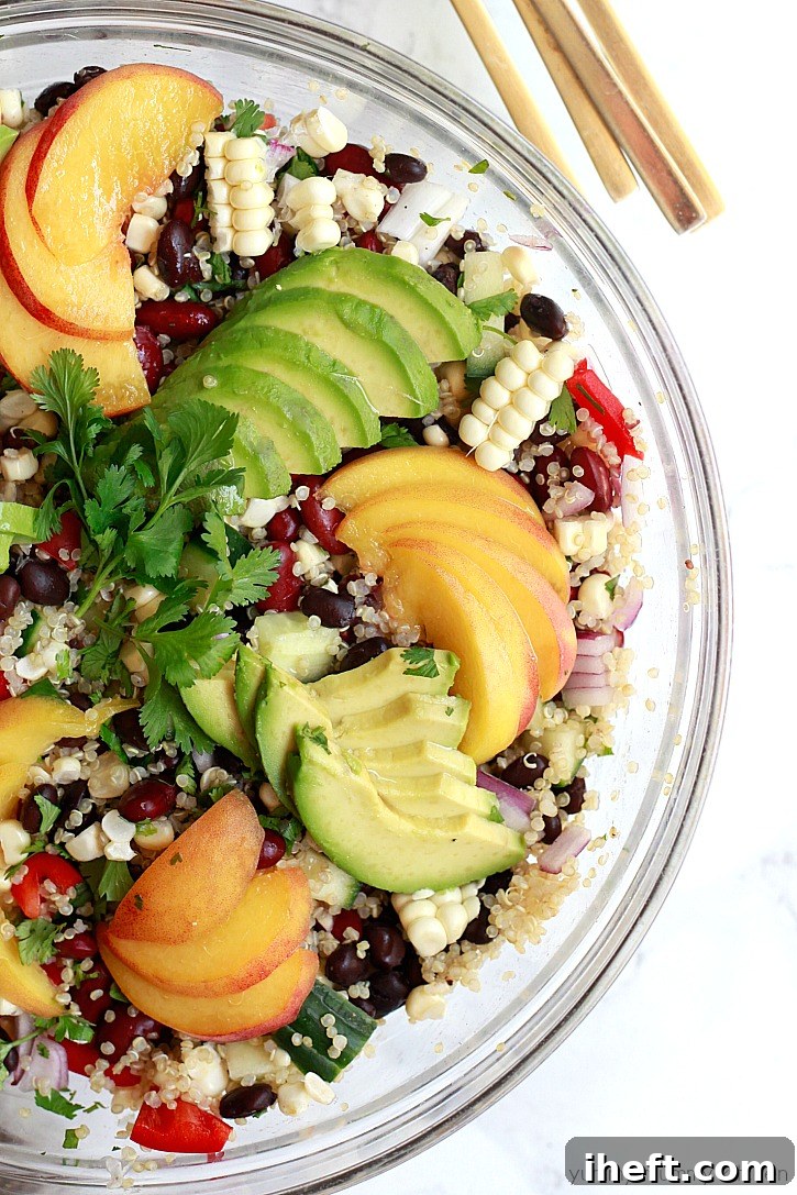 An artistic close-up shot of the stunning quinoa salad featuring black beans, corn kernels, vibrant bell pepper strips, creamy avocado slices, and juicy peach chunks. This visually appealing and hearty vegan quinoa salad is the perfect centerpiece for any summer gathering or an excellent choice for convenient meal prep lunches at home.