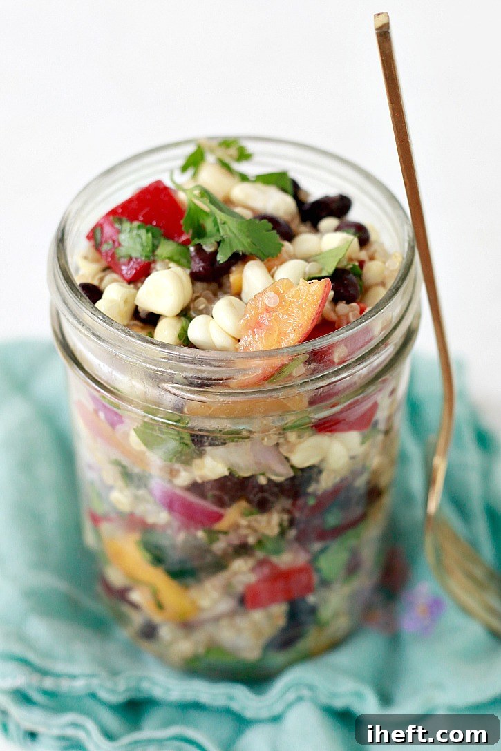 A perfectly portioned jar of this Mexican-inspired vegan quinoa salad, showcasing its layers of colorful ingredients, makes for a delicious, convenient, and healthy lunch option on the go.