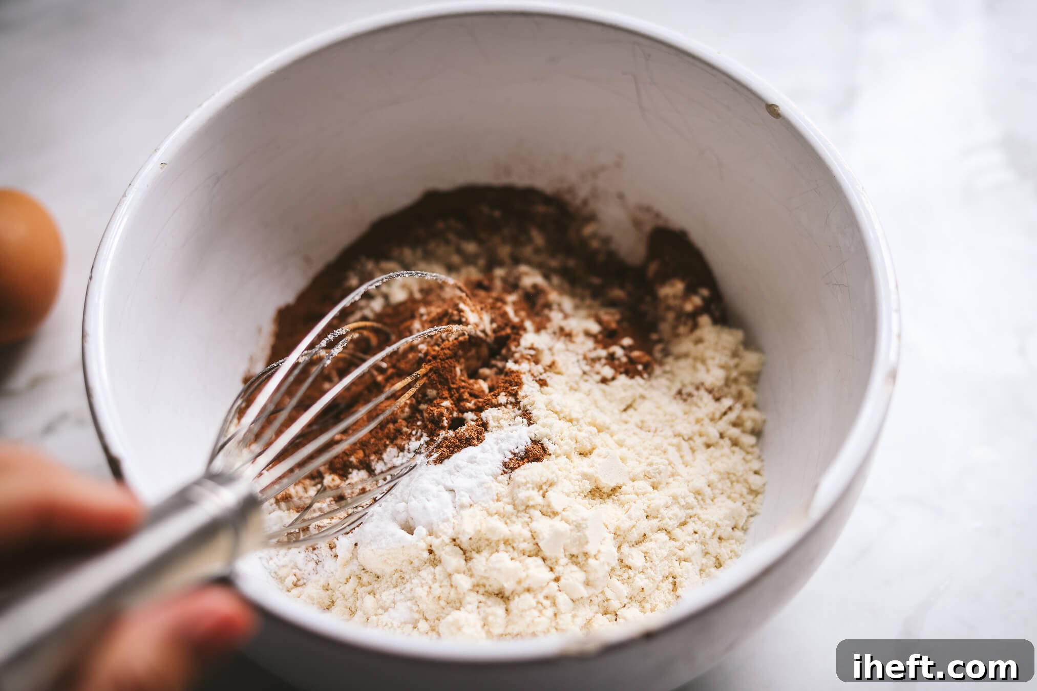 The dry ingredients for grain free pumpkin bread are whisked together in a bowl.